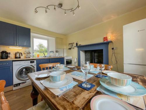 a kitchen with a wooden table with plates and wine glasses at Dalcharn in Bettyhill