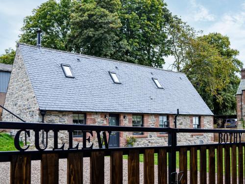 a house with a black roof and a wooden fence at Cullew Bothy in Pearsie