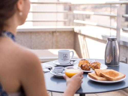 a woman sitting at a table with a plate of breakfast food at Abba Sants in Barcelona