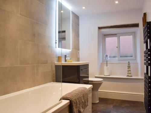 a bathroom with a tub and a toilet and a window at Sunnydene in Staithes