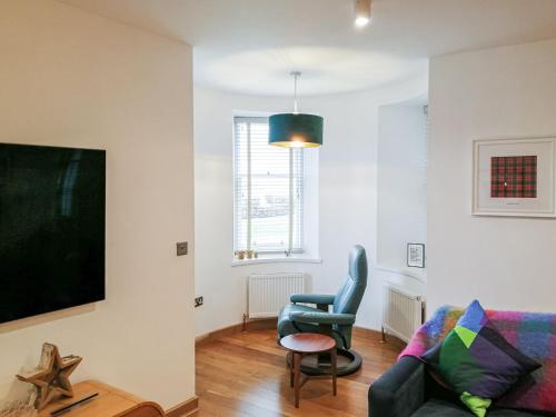 a living room with a couch and a chair at Kilbowie Retreat in Oban