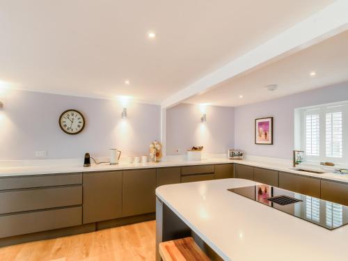a kitchen with white counters and a clock on the wall at Point House in Milford Haven