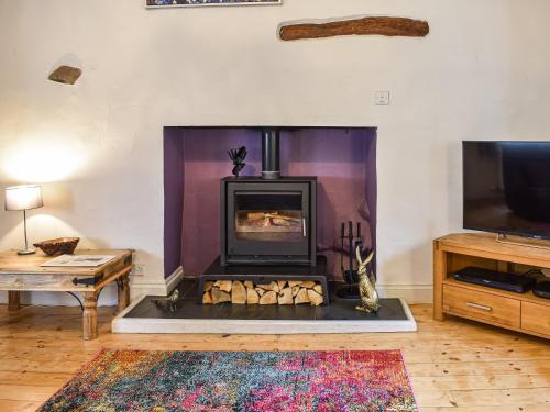 a living room with a fireplace and a tv at Forge Cottage in Keswick