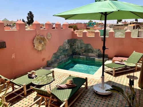 una piscina con sombrilla y sillas y una mesa con sombrilla en Riad Aya, en Marrakech