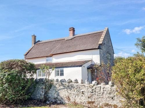 a small white house with a stone wall at The Moat House in Cudworth