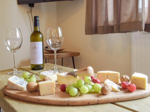 eine Holzschnitttafel mit Käse und Weingläsern in der Unterkunft Caws Cottage - Lancych in Cenarth