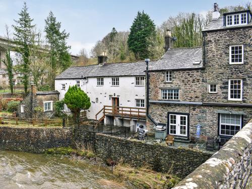 ein altes Steinhaus neben einem Fluss in der Unterkunft Forge Cottage in Keswick