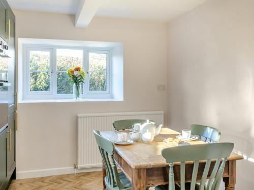 a kitchen with a wooden table with chairs and a window at The Moat House in Cudworth