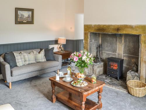 a living room with a couch and a fireplace at Allotment Cottage in Rothbury
