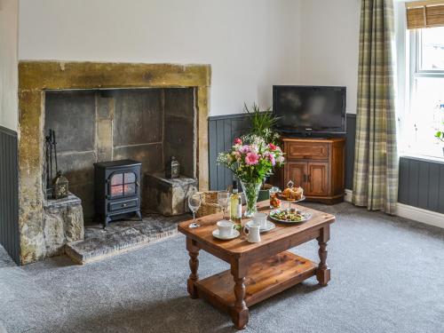 a living room with a fireplace and a table with flowers at Allotment Cottage in Rothbury