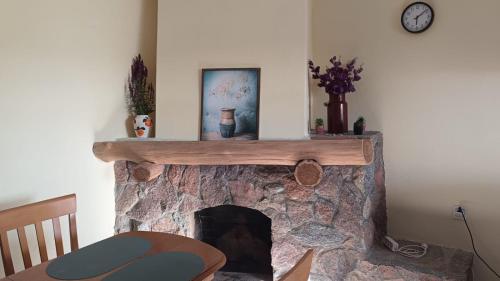 a living room with a stone fireplace with a clock at Domek w pięknej okolicy in Chmielów