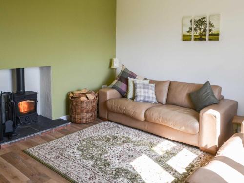 a living room with a couch and a fireplace at Low Chibburn Farm Cottage in Hadston