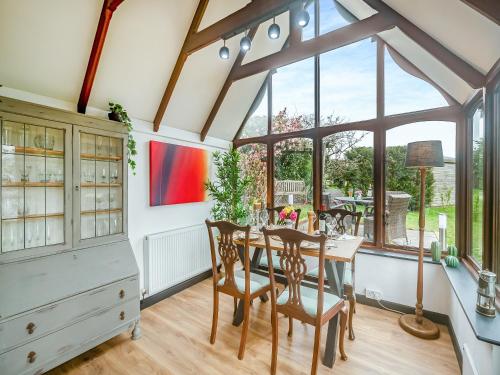 a dining room with a table and chairs and a large window at The Loft in Yealmpton