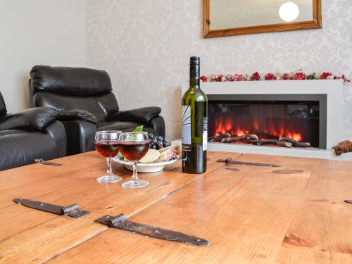 eine Flasche Wein und zwei Gläser auf einem Holztisch in der Unterkunft High Threave Cottage in Kirkcowan