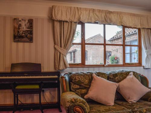 a living room with a couch and a piano at Glossoms Lodge in Scalford
