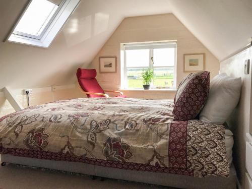 a bedroom with a bed and a red chair at Rookmead Cottage in Yarmouth
