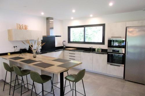 a kitchen with a wooden table and green chairs at Spacious house with garden in Soustons