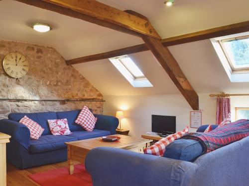 ein Wohnzimmer mit zwei blauen Sofas und einer Uhr in der Unterkunft Stable Cottage in Oswestry