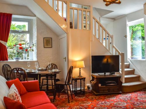 a living room with a couch and a tv and a table at Kiln Cottage in Bolton le Sands