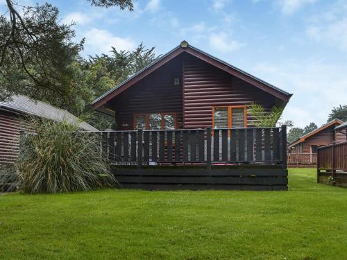 Una cabaña de troncos con una gran terraza en un patio. en Folly Lodge, en Sewerby