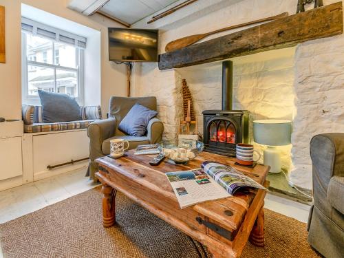 a living room with a wooden table and a wood stove at Fishermans Cottage in St Ives
