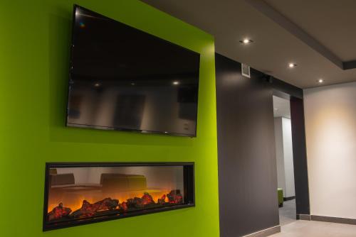a green wall with a flat screen tv above a fireplace at Hotel V in Gatineau