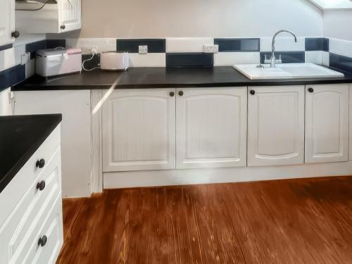 Una cocina con gabinetes blancos y un fregadero. en Stewards Granary - Uk48306, en Berwick-Upon-Tweed