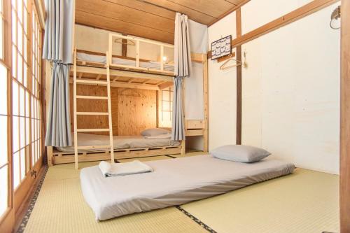 a room with two bunk beds and a ladder at KARASUYA GuestHouse in Takasaki