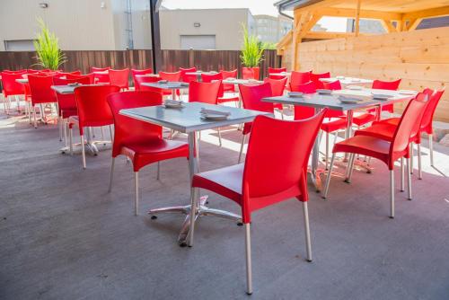 a row of tables and chairs with red chairs at Hotel V in Gatineau