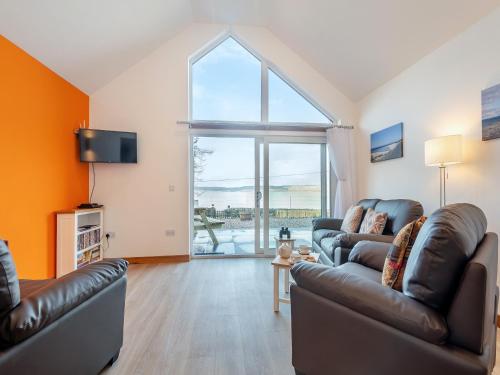 a living room with two couches and a large window at Postbox Cottage in Catacol
