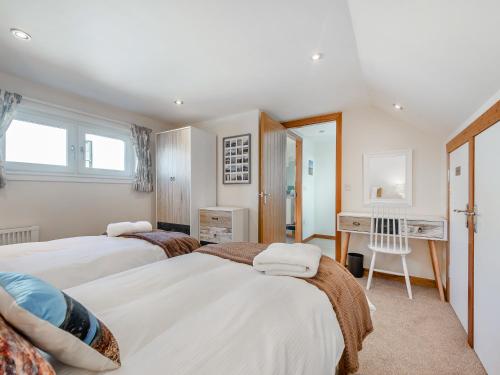 a bedroom with two beds and a desk at Postbox Cottage in Catacol