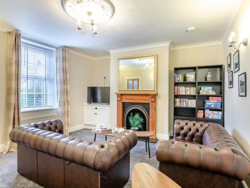 a living room with two leather couches and a fireplace at Lundy Cottage in Alnwick