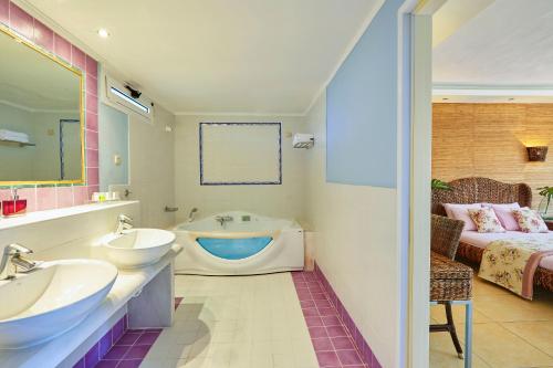 a bathroom with two sinks and a bath tub at Ilio Mare Hotel in Prinos