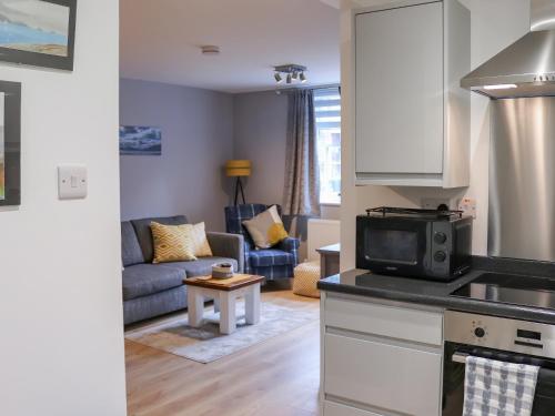cocina y sala de estar con sofá y microondas en Llety Cariad, en Bala