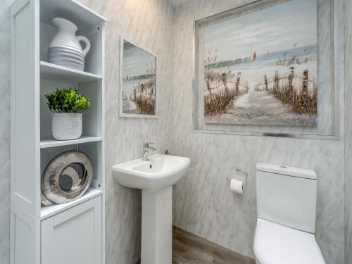 a white bathroom with a sink and a toilet at The Mulberry in Lamlash