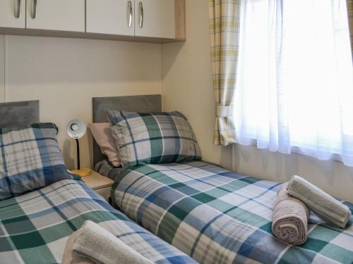 two twin beds in a small room with a window at Lodge 46 - Uk49669 in Bridlington