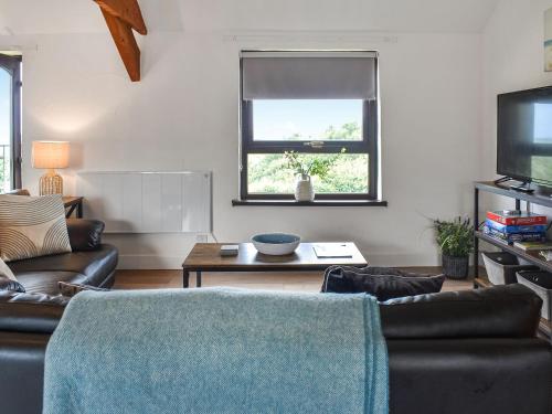 ein Wohnzimmer mit Sofa und Fernseher in der Unterkunft Dizzard Cottage in Bude
