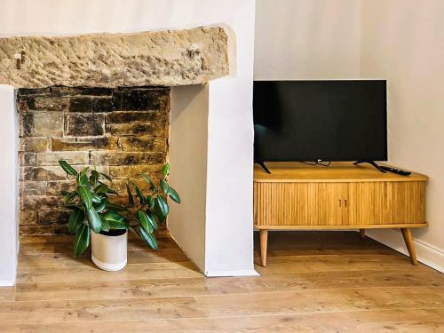 a living room with a television on a wooden stand at Saltaire Mill Cottage in Saltaire