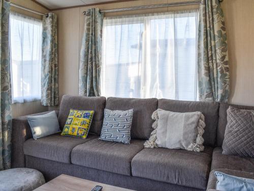 ein Wohnzimmer mit einer braunen Couch mit Kissen in der Unterkunft Sunningdale in Westward Ho