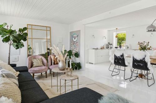 a living room with a couch and chairs and a kitchen at Idyllic Cliffside Villa With Stunning Sea Views in Sandvig