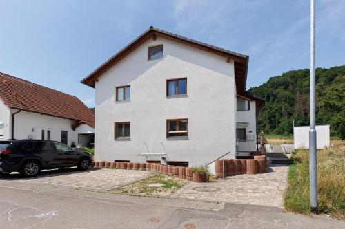 a white house with a car parked in front of it at Bergblick Apartments in Radolfzell am Bodensee