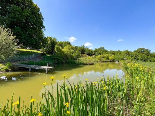 a pond with a bench in a park with flowers at Wendys Wing - Uk49742 in Fulletby