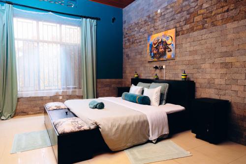 a bedroom with a large bed and a brick wall at Ibuye Villa Holiday Home in Nyakinama