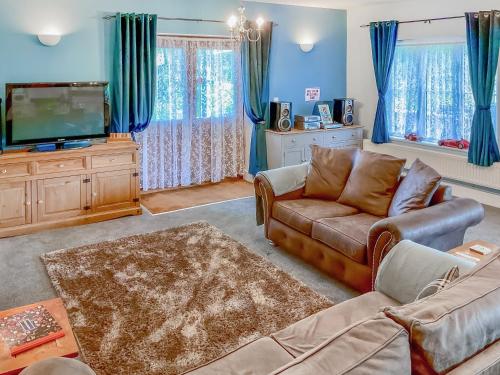 a living room with a couch and a tv at Court Place in Misterton