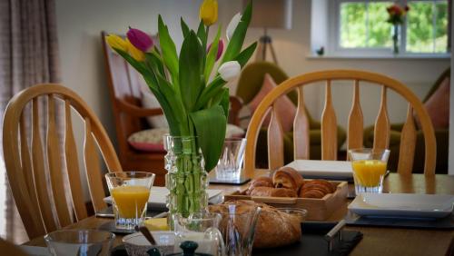 a dining room table with a vase of flowers and bread at Drefach - Refurbished farmhouse in stunning surroundings with hot tub in Llanwinio