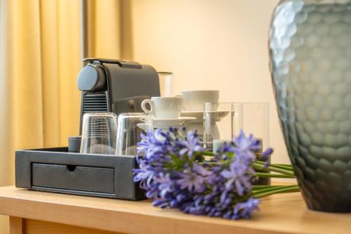 a table with a vase and purple flowers on it at Seehotel am Kaiserstrand in Lochau