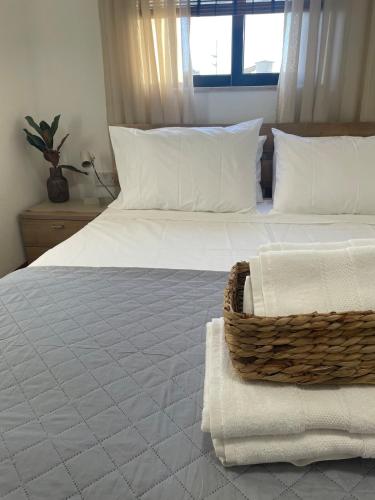 a bedroom with two beds with white sheets and a basket at Bright & Airy 3 Bedroom Apartment in Naxxar