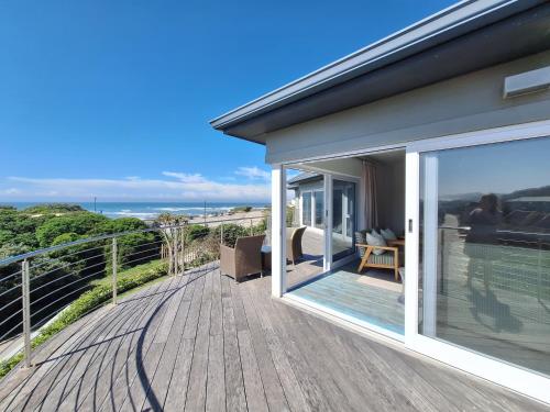 a house with a deck with a view of the ocean at Seaside Beach House with Pool & Invertor in Port Alfred