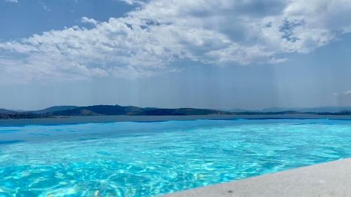 une grande piscine d'eau bleue avec des montagnes en arrière-plan dans l'établissement Villa Infinity, à Néa Péramos