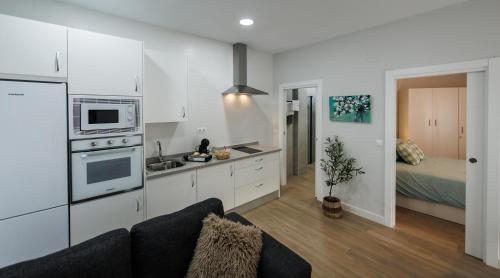 a kitchen with a couch and a bed in a room at Apartamentos LUXURY SUITES MACABEO in Almendralejo